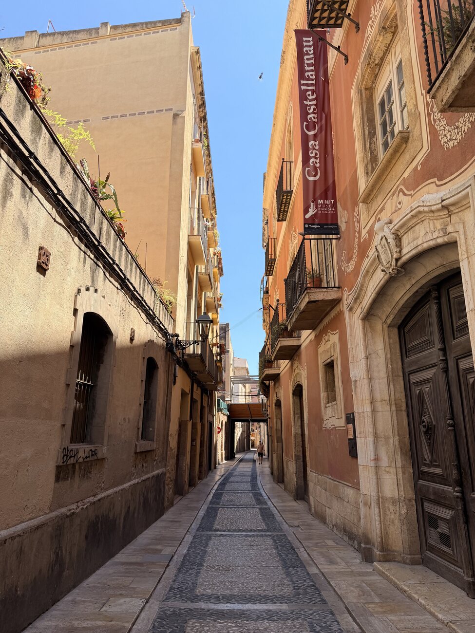 A narrow sunlit alley of terracotta buildings in Tarragona, Spain