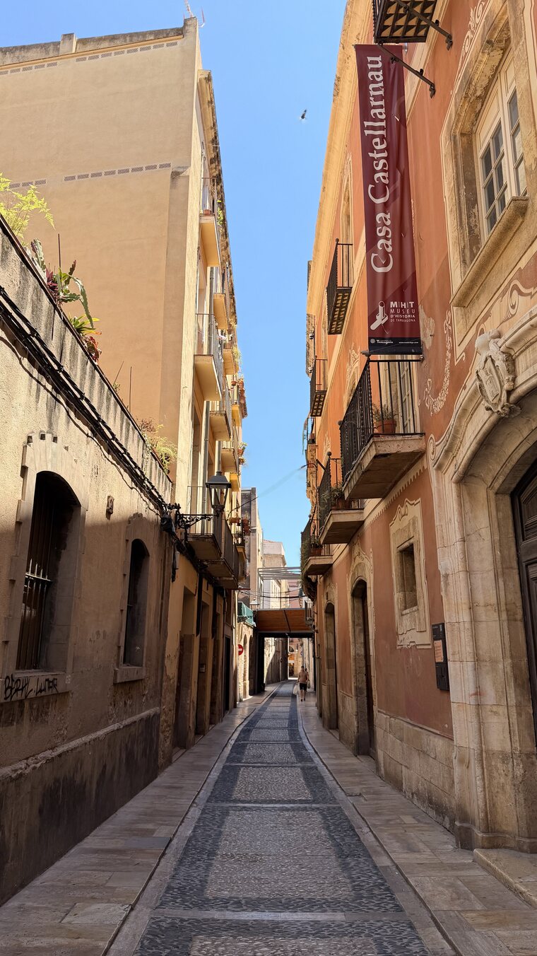 A narrow sunlit alley of terracotta buildings in Tarragona, Spain