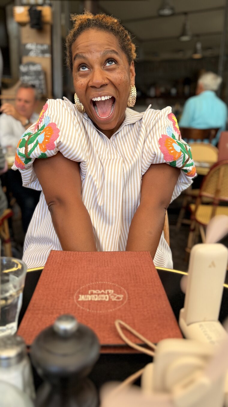 Brandi reacting with delight to a menu at an outdoor cafe