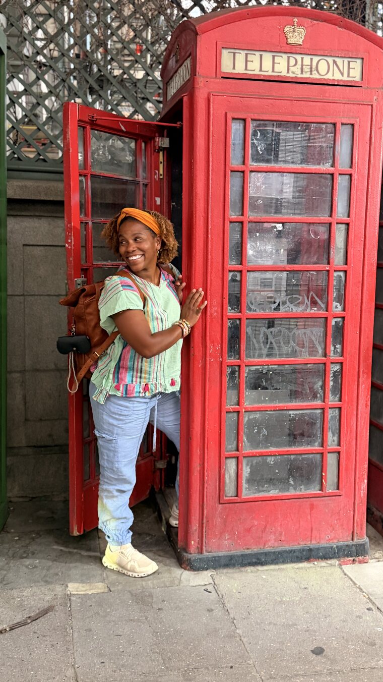 Brandi laughing in the doorway of a red London telephone box