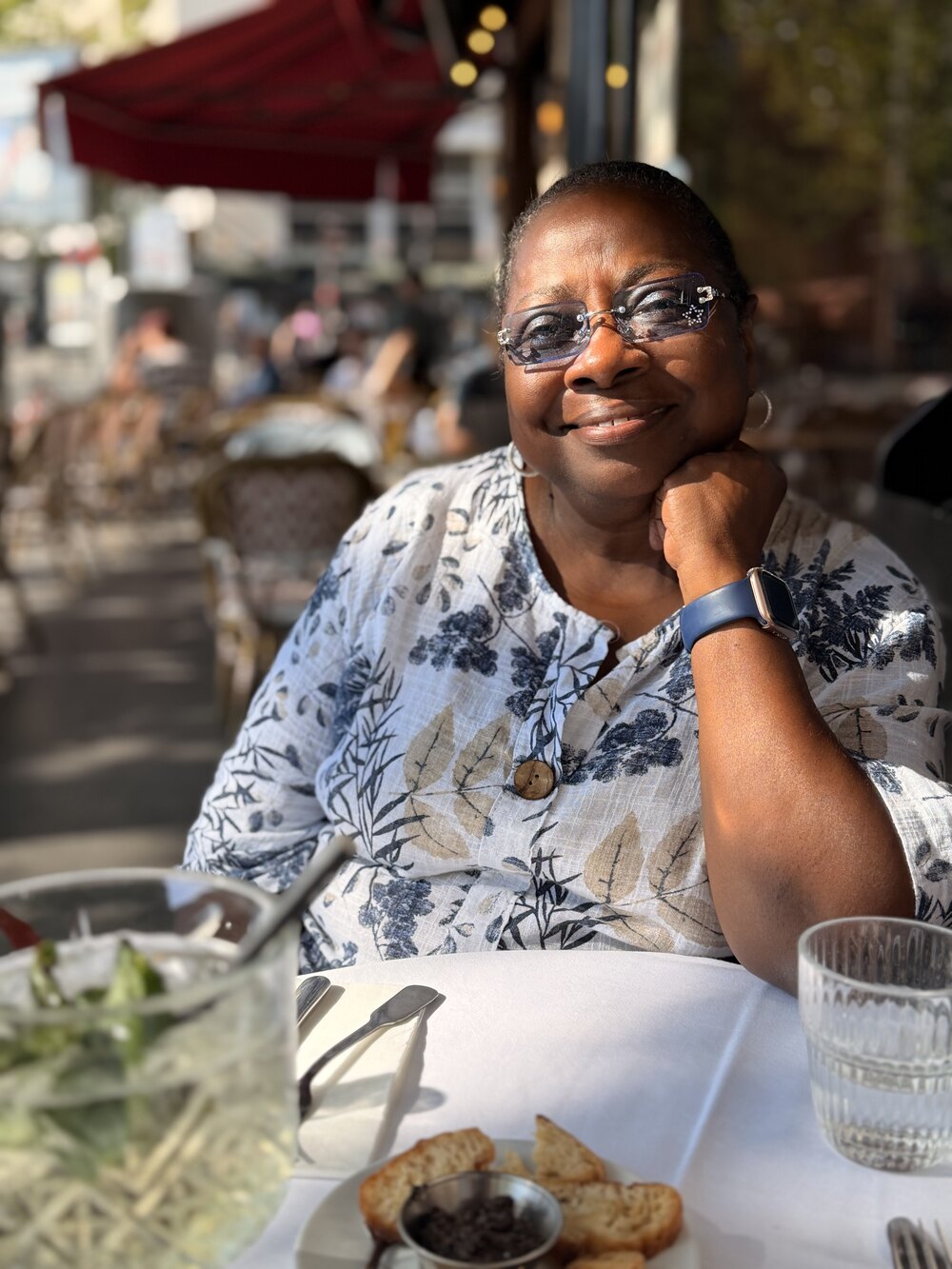 Sandra sitting at a sunny outdoor cafe table